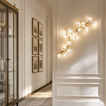 A modern wall sconce featuring an antique brass branch-like metal frame adorned with textured circular glass blossom shades.
