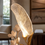 A sculptural floor lamp with a textured antique gold tree branch base and frosted glass leaf-shaped shades.
