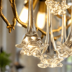 A sculptural wall sconce shaped like a tree branch with a textured gold finish and cascading faceted crystal teardrop prisms.