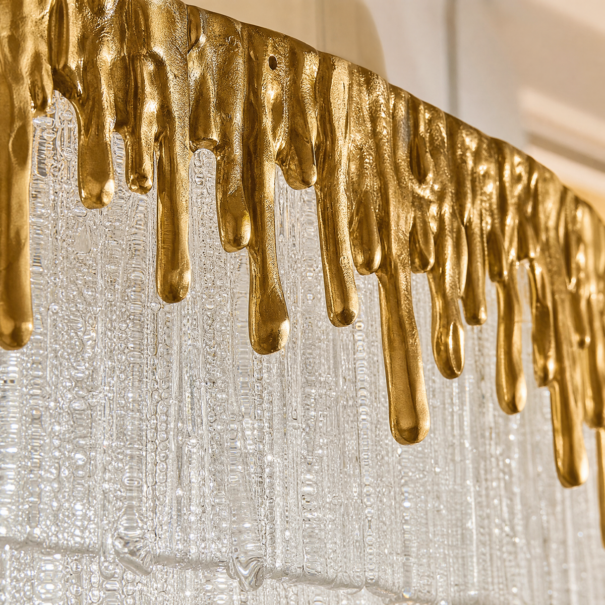 An oval crystal fringe chandelier with a warm gold textured metal band and multiple tiers of frosted icicle glass rods.