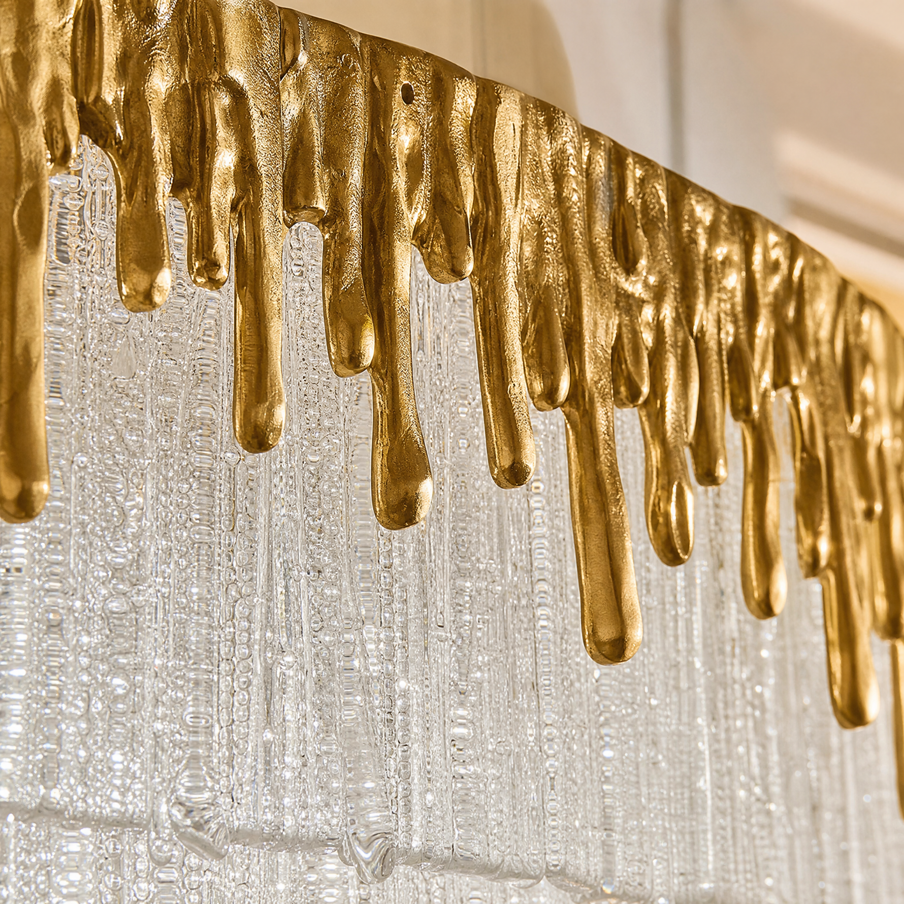 An oval crystal fringe chandelier with a warm gold textured metal band and multiple tiers of frosted icicle glass rods.