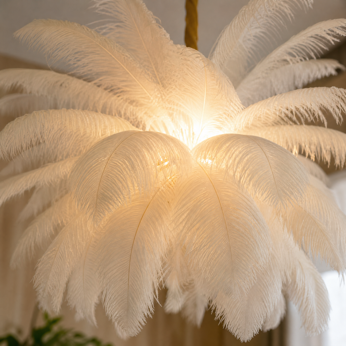 A round pendant chandelier featuring layers of white ostrich feathers and brushed brass hardware hanging in a modern space.