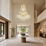 A large gold branch chandelier with tiered cascading crystal raindrop strands hangs against a neutral background.
