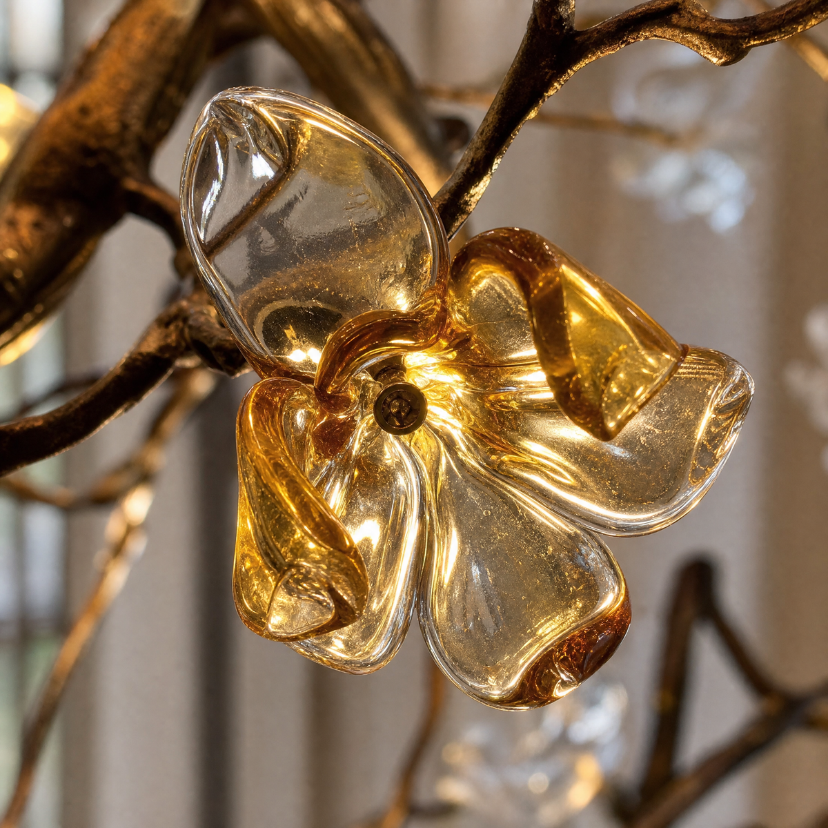 A tall gold cascading chandelier featuring metallic branches and crystal glass blossoms hanging in a high-ceiling space.