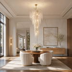A multi-tiered cascading crystal chandelier with a gold frame hangs in a grand foyer with a curved staircase.