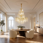A large, multi-tiered chandelier with a gold branch-like frame and long strands of cascading crystal droplets.