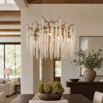 A circular antique gold branch chandelier with cascading crystal bead strands hangs from the ceiling in a lit room.