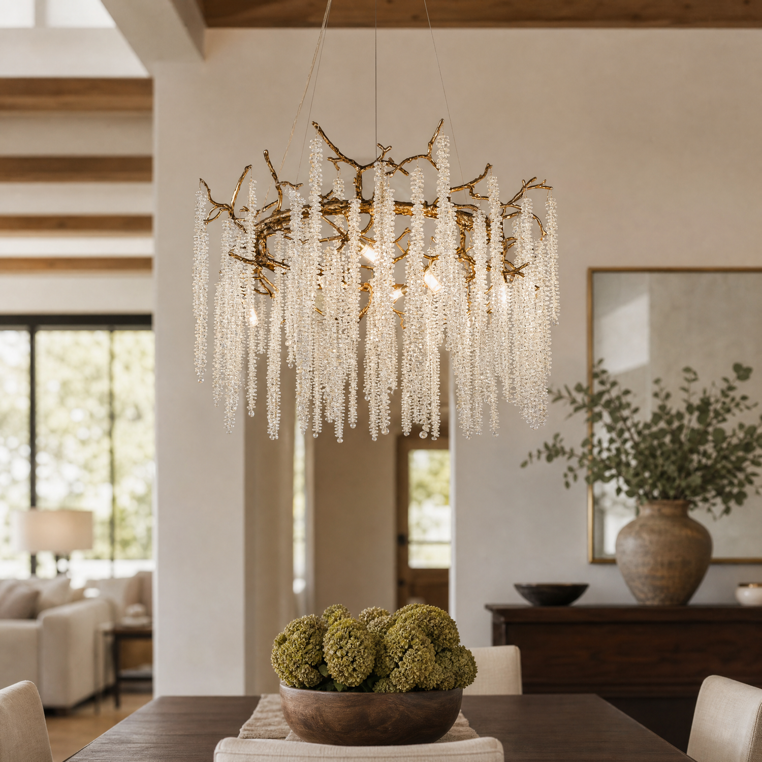 A circular antique gold branch chandelier with cascading crystal bead strands hangs from the ceiling in a lit room.