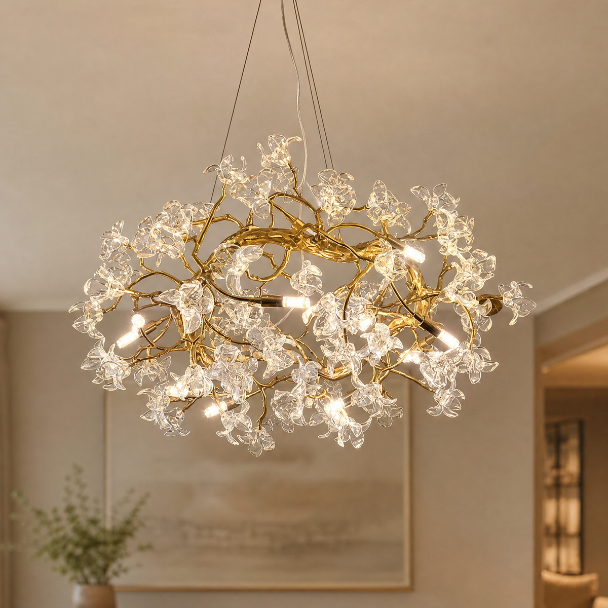 A modern organic chandelier features a warm antique brass branch frame decorated with twelve clear sculpted glass blossoms.