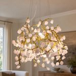 A branching metal chandelier finished in warm brass featuring clusters of raw rose quartz crystals.