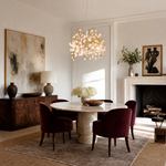 A branching metal chandelier finished in warm brass featuring clusters of raw rose quartz crystals.