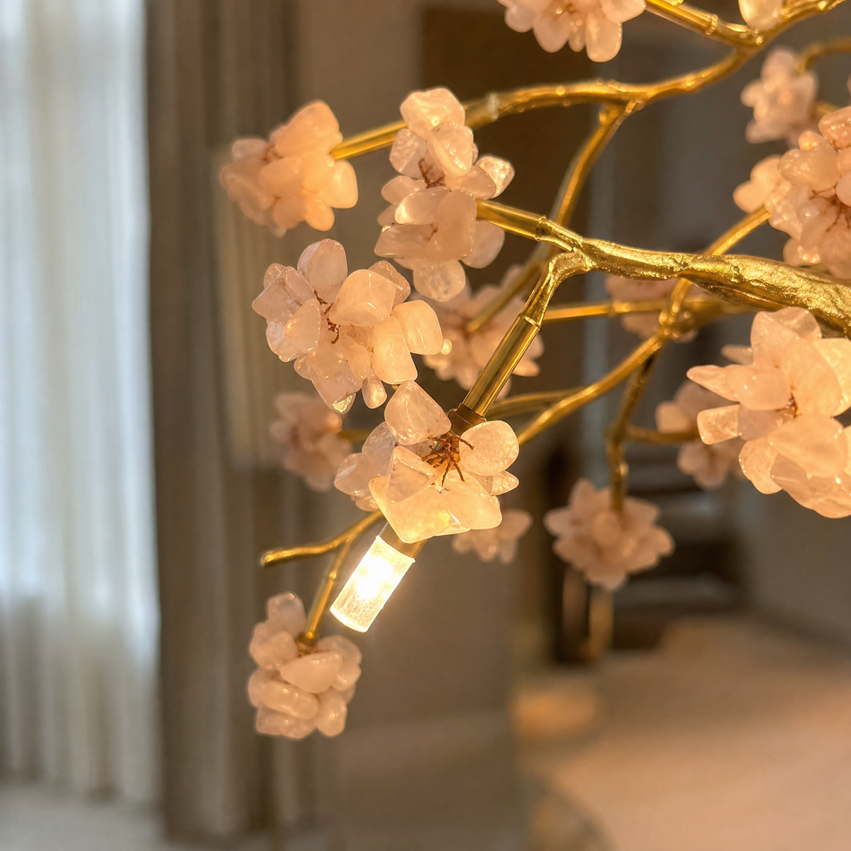 A circular gold metal ring chandelier decorated with pink crystal floral blooms and internal G9 light sockets.