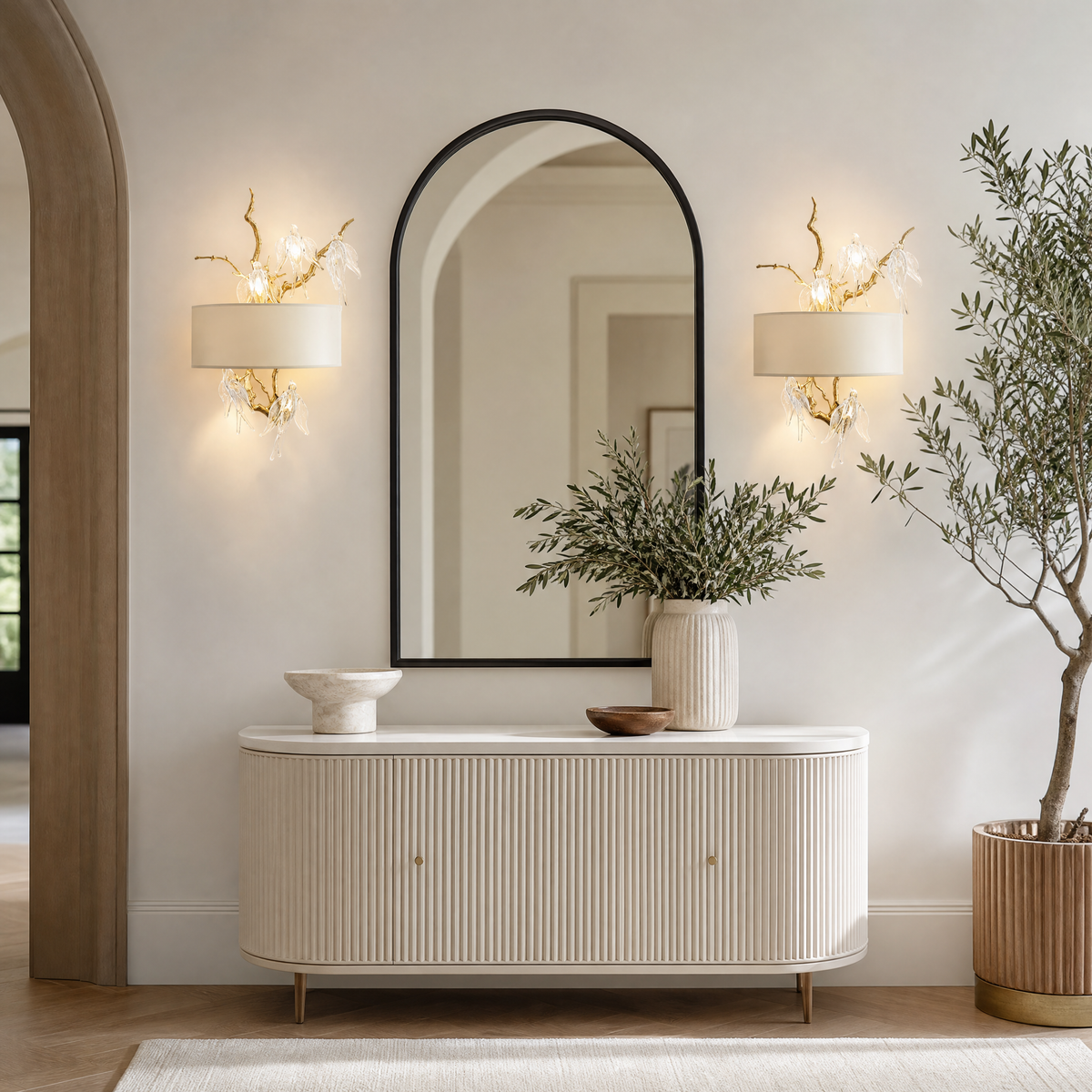 A gold metal branch wall sconce with clear crystal songbird accents and an off-white fabric drum shade.