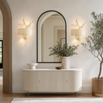 A gold metal branch wall sconce with clear crystal songbird accents and an off-white fabric drum shade.