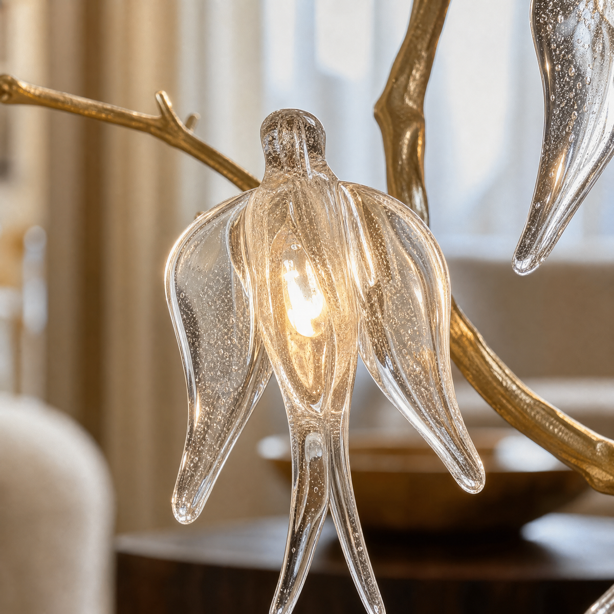 A gold metal branch wall sconce with clear crystal songbird accents and an off-white fabric drum shade.