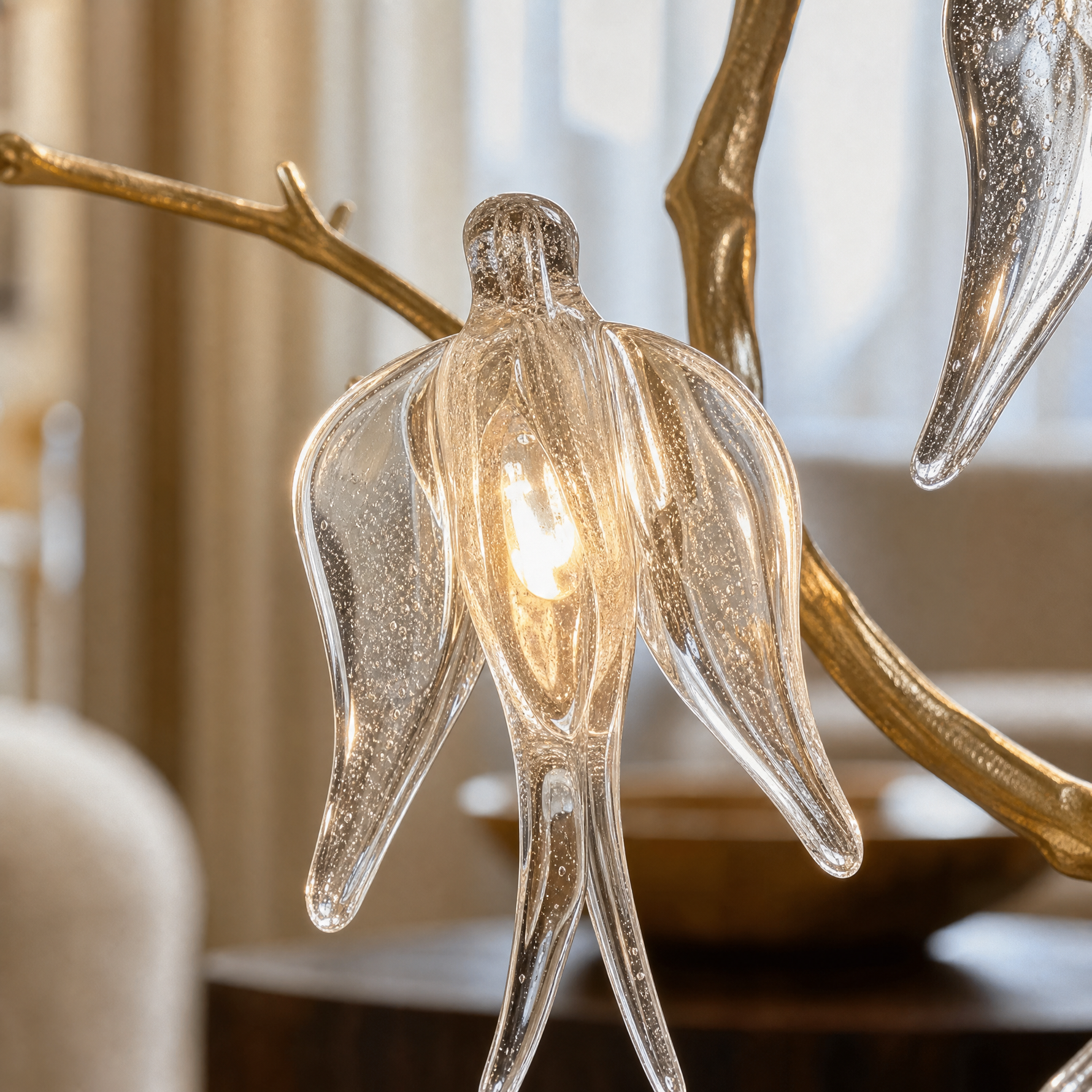 A gold metal branch wall sconce with clear crystal songbird accents and an off-white fabric drum shade.