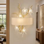 A gold metal branch wall sconce with clear crystal songbird accents and an off-white fabric drum shade.