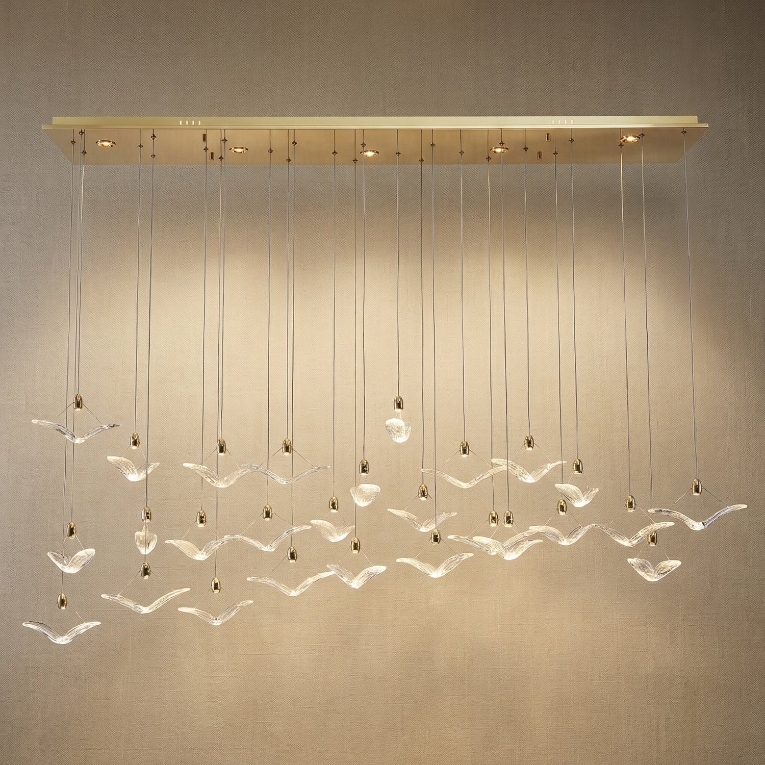 Modern dining room cascading glass chandelier over long oak dining table — Yiosi Crane linear pendant