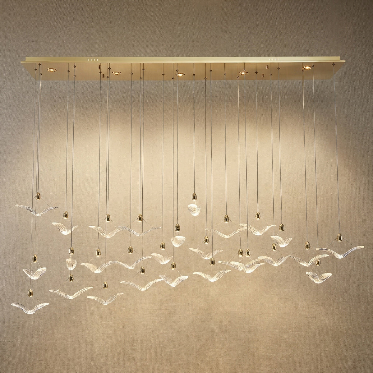 Modern dining room cascading glass chandelier over long oak dining table — Yiosi Crane linear pendant
